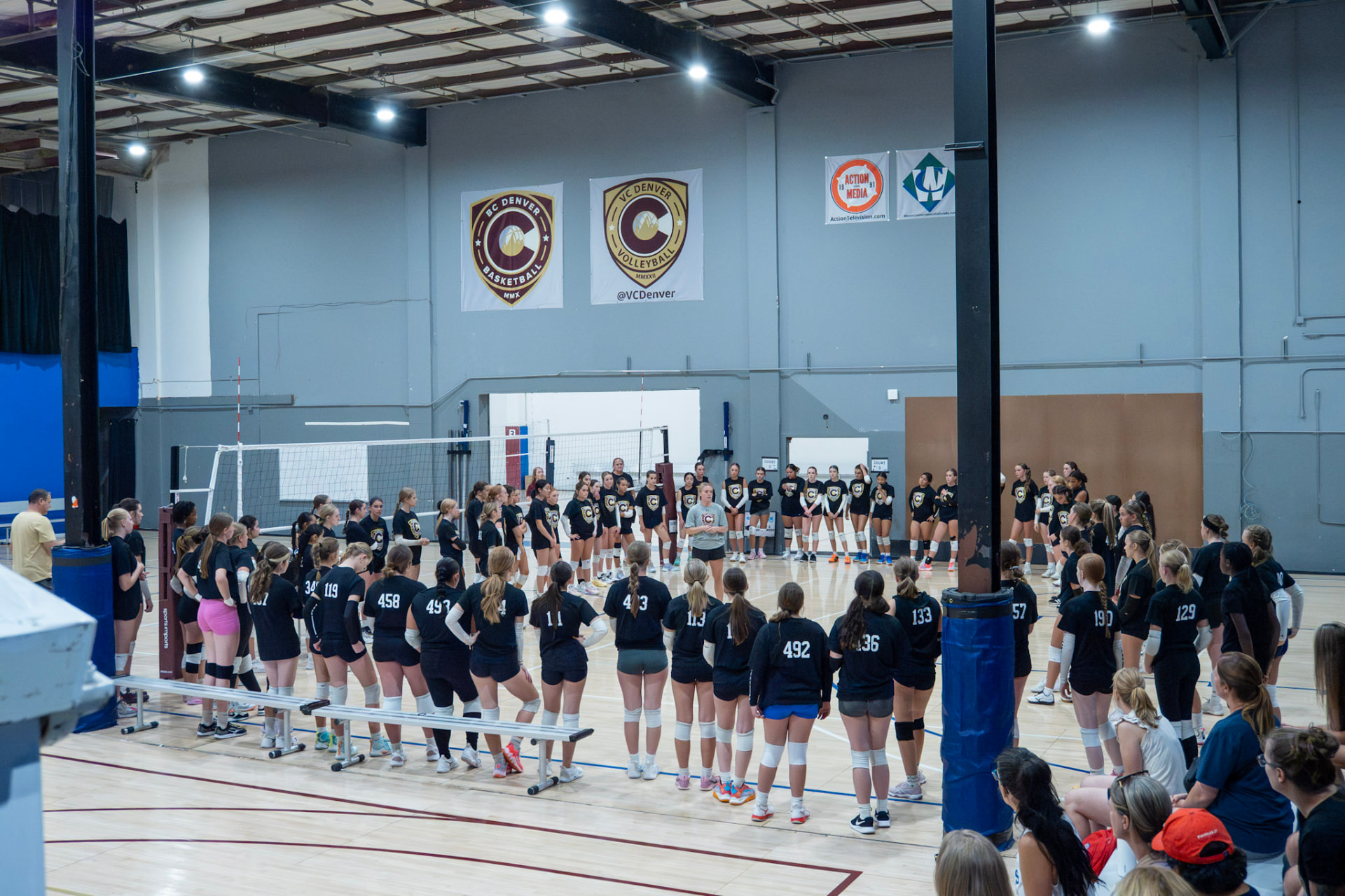 VC Denver volleyball athletes gathered around a court for a club meeting